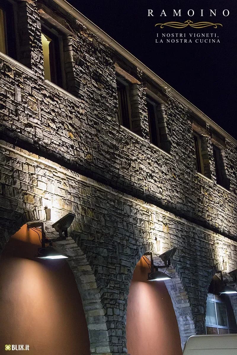 La facciata in pietra del ristorante Ramoino illuminata di sera